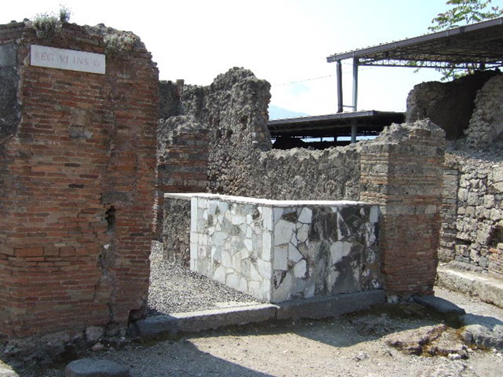 VI.4.1 Pompeii. May 2006. Entrance doorway with counter. 
According to Curti, in 1818, in the face of the Via Domiziana [todays Via Consolare], on the corner of a triangular insula, was found a taberna of a seplasarius [a trader in perfumes and unguents] or a pharmacist. For exhibition, he had painted a large snake that bites a pine cone. The serpent was the attribute of Hygeia, the goddess of health, and of Aesculapius: it is still the emblem of today's [1873] pharmacies. In Pompeii, as we have noted elsewhere, it was valid for other purposes, and therefore would not have been enough to fix the designation of this taberna as a pharmaceutical workshop, had it not been found inside various other medicines, chemical preparations, pots with dried medicines and pills, spatulas, and a bronze box with compartments containing drugs, and a porphyry blade to spread and smooth the poultices.
See Curti P. A., 1873. Pompei e le sue rovine: Part 2. Napoli e Milano, p. 268.
According to Della Corte, this thermopolium or workshop was always described in the old bibliographies as an officina farmaceutica
Why?  Many chemical preparations and many jars with dried medicines and pills were found here.
As medical substances, they are unknown, however as the results have never been analysed. 
The notion that it was an officina farmaceutica, however was, and stays, simply circumstantial.
See Della Corte, M., 1965.  Case ed Abitanti di Pompei. Napoli: Fausto Fiorentino. (p.42)
