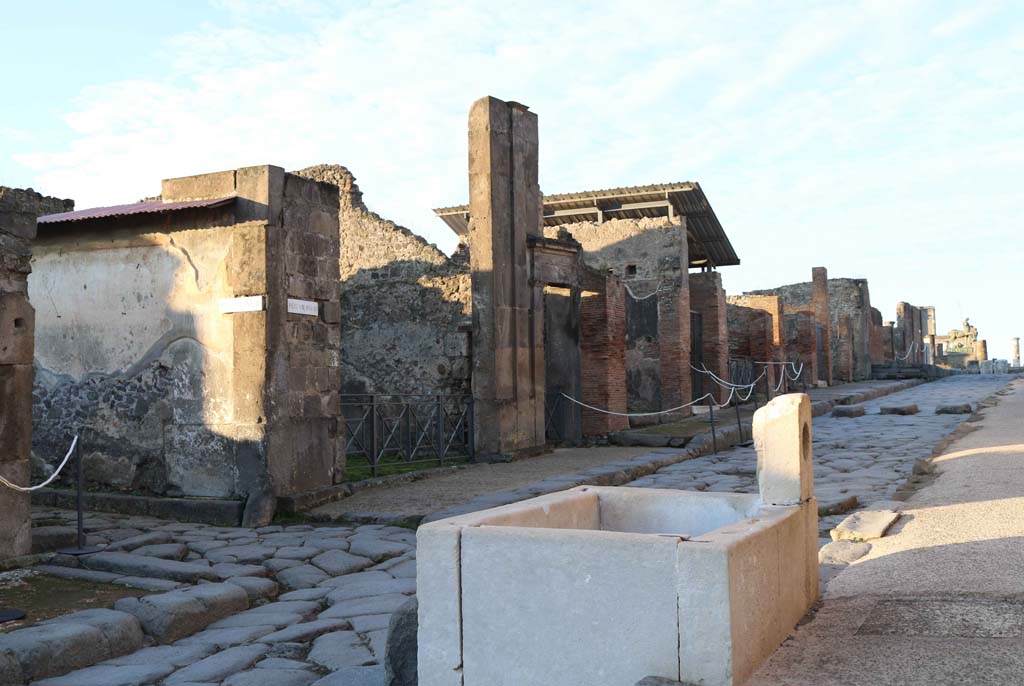 Via dellAbbondanza, south side, Pompeii. December 2018. 
Looking south-west across fountain at VII.9.67/68, towards north side of Insula VIII.3. Photo courtesy of Aude Durand.
