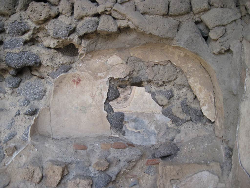 I.3.5 Pompeii. September 2010. Detail of niche in rear east wall on south side. Photo courtesy of Drew Baker. According to Boyce, this broad arched niche in the east wall, originally had its walls coated with white stucco. The stucco was painted with red, blue and green flowers and plants. Eventually, a layer of red stucco was spread over the top, and since peeling off, had revealed the earlier layer underneath. See Boyce G. K., 1937. Corpus of the Lararia of Pompeii. Rome: MAAR 14. (p.24) 
