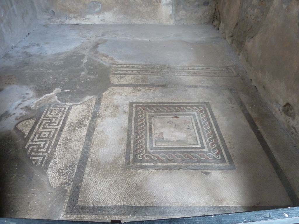 I.10.4 Pompeii. May 2010. Room 21 with floor mosaic for two-side beds or couches, with emblema in centre.