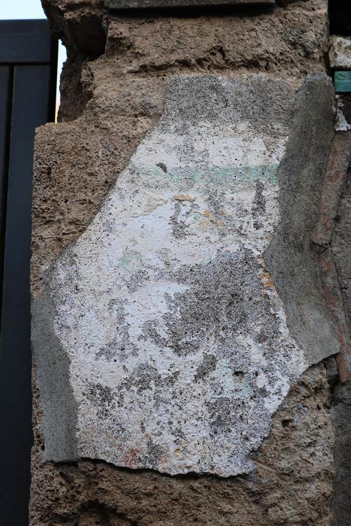 I.12.11 Pompeii. December 2018. Pilaster on east of entrance doorway, site of wall painting of Hercules.
Remains of painted plaster on east side of doorway, the remains of the garland are just visible.
Photo courtesy of Aude Durand.
