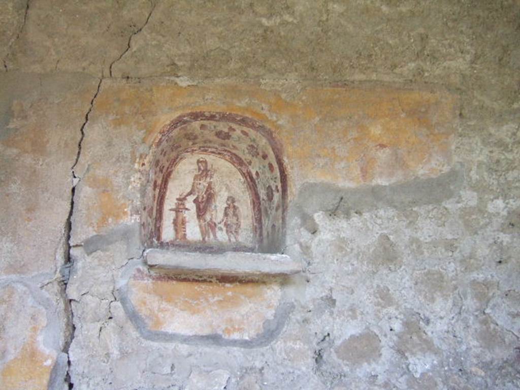 I.17.4 Pompeii. May 2006. Lararium niche on west wall of peristyle garden.  
A genius is making an offering at a round altar. A small camillus is to his left.
The side walls are painted with red flowers possibly roses.
On the yellow-coloured wall outside the niche, a colour trail is visible on the right, which perhaps belongs to a big snake. A paint ridge above the niche may perhaps be interpreted as a garland.
See Frhlich, T., 1991. Lararien und Fassadenbilder in den Vesuvstdten. Mainz: von Zabern, L37, p. 264, taf. 9,1.
