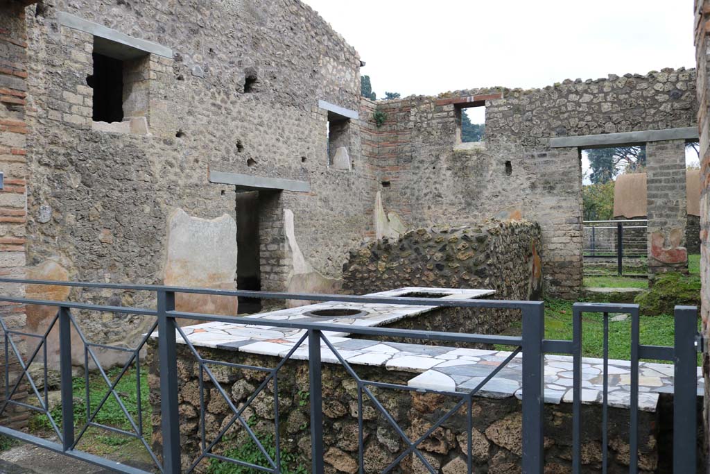 II.4.7 Pompeii. December 2018. Thermopolium.
Looking south-east across bar-room from entrance on Via dell’Abbondanza to doorway to room with multiple seating and tables. 
Photo courtesy of Aude Durand.

