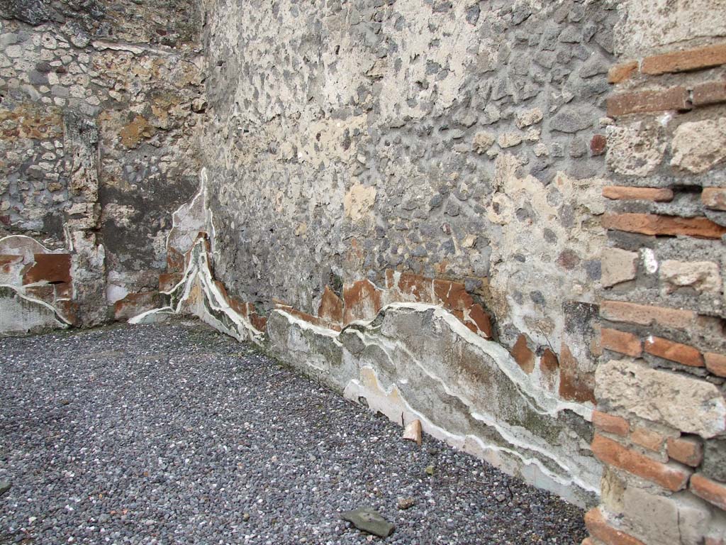 VI.7.23 Pompeii. December 2006. Walls showing remains of many levels of painted plaster in triclinium.
Looking west along north wall of triclinium. The west and north walls were faced with tegulae mammatae. 
