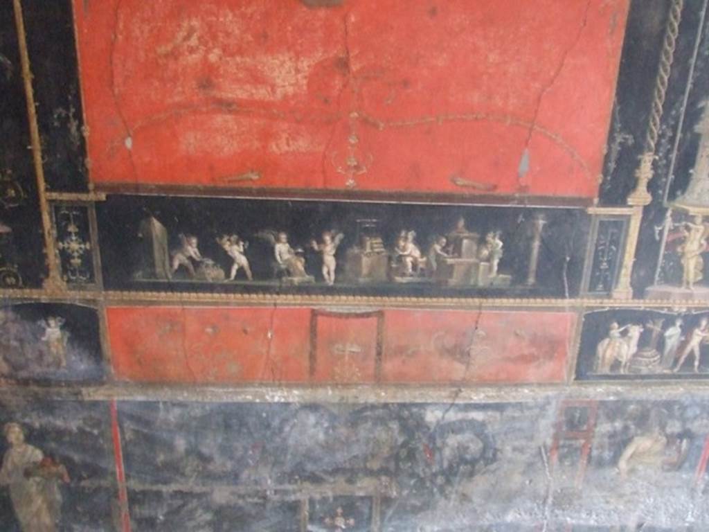 VI.15.1 Pompeii. December 2006. Room of the Cupids or Cherubs. 
Painting of Cupid Goldsmiths.  Below left is a female figure or priestess holding an implement of sacrifice.  Below right are the remains of a painting of an Amazon with a shield.
