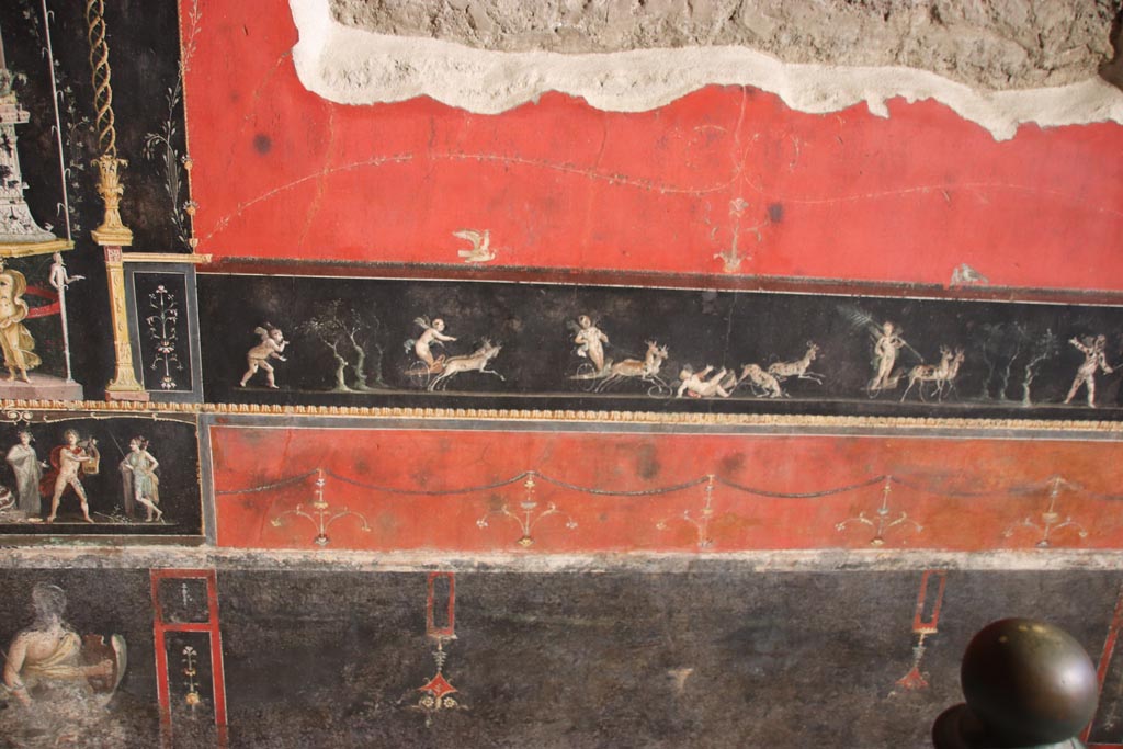 VI.15.1 Pompeii. October 2023. 
Central panel in predella on east wall with painted panel of cupids in a race between chariots pulled by deer. Photo courtesy of Klaus Heese.
