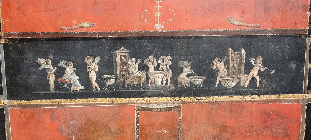 VI.15.1 Pompeii. January 2023. East wall with painted panel of cupids making perfumed oil. Photo courtesy of Miriam Colomer.