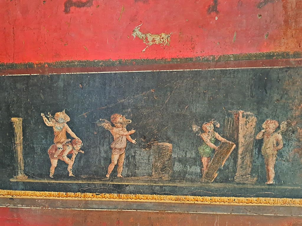 VI.15.1 Pompeii. April 2023. 
Detail of cupids from south wall in south-east corner, taking part in an archery or throwing contest.  Photo courtesy of Giuseppe Ciaramella
