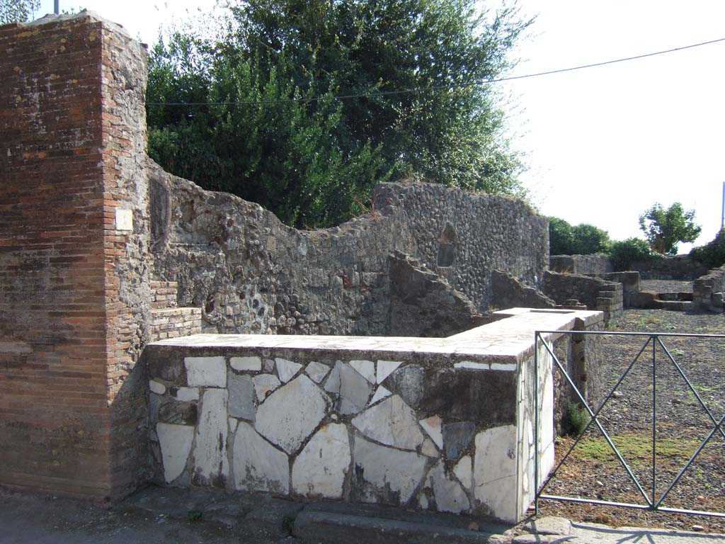 VI.17.4 Pompeii. September 2005. Two-sided marble counter with hearth and display shelves.