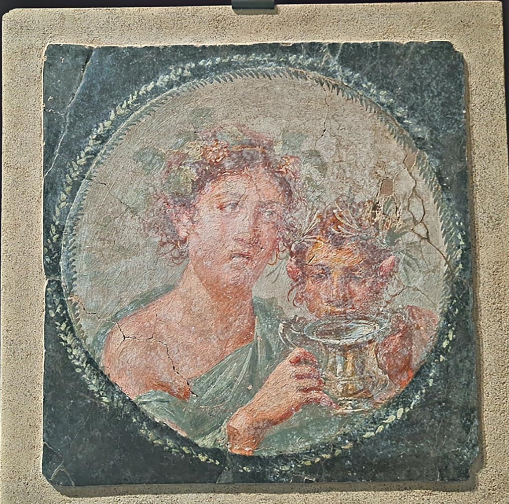 VI.17.42 Pompeii. April 2022. 
Medallion depicting Maenad and a young Satyr, from west end of the north wall of the large triclinium. On display in exhibition in Palaestra. 
Photo courtesy of Giuseppe Ciaramella.
