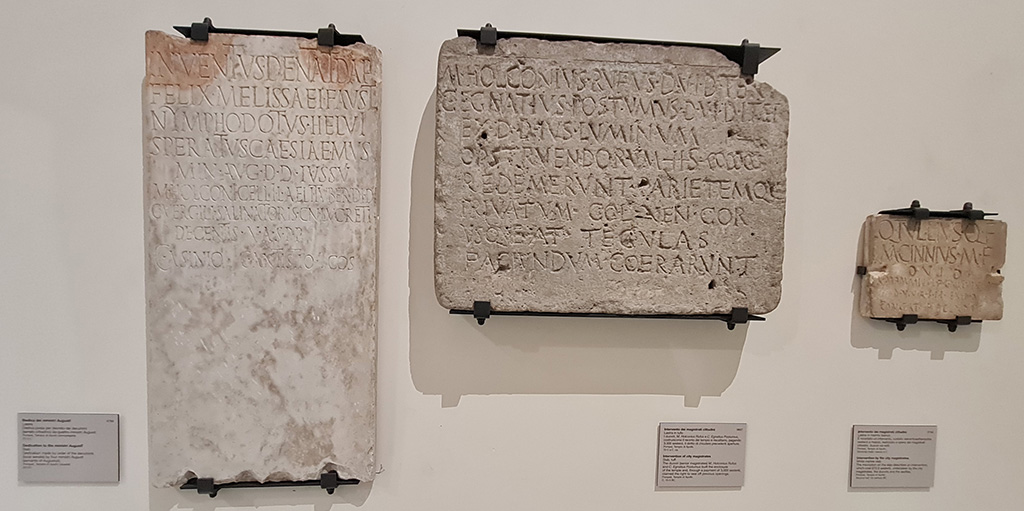 VII.7.32 Pompeii. 
On left: Dedication to Ministri Augustali, on display in “Campania Romana” gallery in Naples Archaeological Museum, inv. 3783. 
Temple of Apollo (but then believed to be the Temple of Venus) (1 Marzo 1823) -

Inventus Dentat(ius) Daph(nus)
Felix Melissaei(!) Faust(us)
Nymphodotus Helvi(us)
Speratus Caesiae Mus(ae)
min(istri) Aug(usti) d(ecreto) d(ecurionum) iussu
M(arci) Holconi Gelli L(uci) Aeli Tuber(onis) d(uumvirorum) i(ure) d(icundo)
C(ai) Vergili Salinatoris Cn(aei) Lucreti
Decentis
[d(uum)vir(orum)] v(iis) a(edibus) s(acris) p(ublicis) p(rocurandis)
C(aio) Asinio C(aio) Antistio co(n)s(ulibus)      [CIL X, 895]

In the centre, on display in “Campania Romana” gallery in Naples Archaeological Museum, inv. 3827.
Temple of Apollo (8 marzo 1817) -

M(arcus) Holconius Rufus d(uum)v(ir) i(ure) d(icundo) tert(ium)
C(aius) Egnatius Postumus d(uum)v(ir) i(ure) d(icundo) iter(um)
ex d(ecreto) d(ecurionum) ius luminum
opstruendorum(!) HS |(mille) |(mille) |(mille)
redemerunt parietemque
privatum col(onia) Ven(eria) Cor(nelia)
usque a<d=T> tegulas
faciundum coera(ve)runt      [CIL X. 787]

On right:
Temple of Apollo, from the room to the north of the portico, also called “sagrestia o cella del sacerdote “ (4 Aprile 1817) , inv. 3763.

Q(uintus) Tullius Q(uinti) f(ilius)
M(arcus) Cinnius M(arci) f(ilius)
d(uum)v(iri) i(ure) d(icundo)
C(aius) Mammius L(uci) f(ilius) C(aius) Naevius M(arci) f(ilius)
d(uum)v(iri) v(iis) a(edibus) s(acris) p(ublicis) p(rocurandis) ex d(ecreto) d(ecurionum)
constat HS DCLXXII s(emis)       [CIL X, 803]

