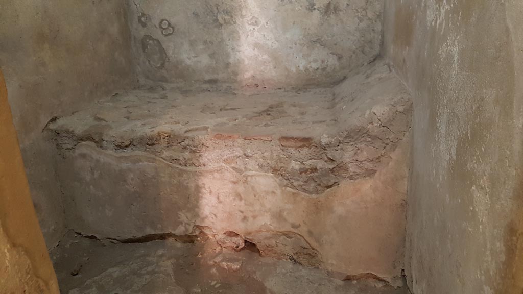 VII.12.8 Pompeii. August 2023. Stone bed with pillow in prostitute’s room. Photo courtesy of Maribel Velasco.
