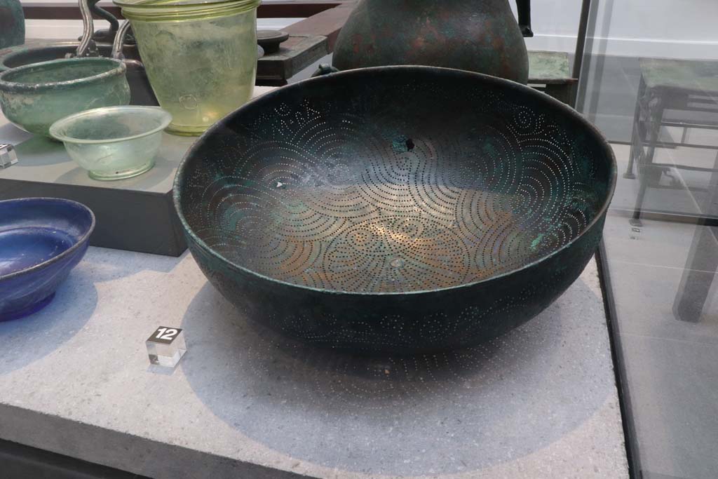 VIII.1.4 Pompeii. February 2021. 
Bronze strainer with inscription, on the left are glass bowls and beakers, all found in House of Menander at I.10.4.
Photo courtesy of Fabien Bièvre-Perrin (CC BY-NC-SA).
