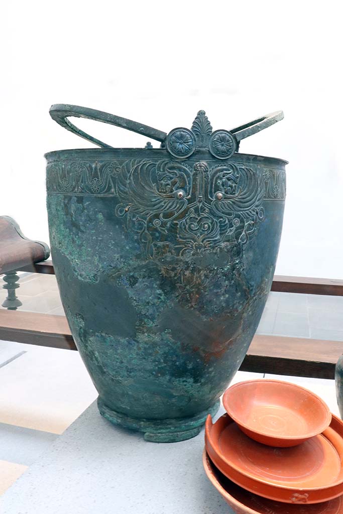 VIII.1.4 Pompeii. February 2021. 
Bronze pitcher with handles decorated with human faces, from House of Menander at I.10.4.
Photo courtesy of Fabien Bièvre-Perrin (CC BY-NC-SA).
