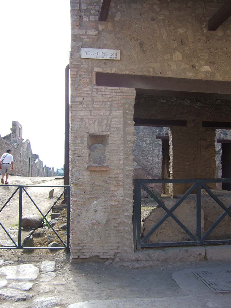 Street shrine or niche outside I.12.5 Pompeii. September 2005.
This is on Via dell� Abbondanza, at the corner with Vicolo dei Fuggiaschi. 
According to Della Corte, on the red pilaster which ended the insula on the east side, two electoral programmes were found.
The first -
GAVIVM II VIR.      [CIL IV 7442]

The second -
AMPLIATVM L F AED
        VICINI
        SVRGITE ET
        ROGATE
        LVTATI F[ac]       [CIL IV 7443]

The first line of the second inscription had larger letters than the subsequent lines.
The text was placed towards the right, because the pilaster was interrupted in the middle by a rectangular niche.
In the niche was fixed a coarse rough stone resembling the outline of a human head, not the usual marble bust, as often seen here and there in the street.
See Notizie degli Scavi, 1914, (p.204).

According to Epigraphik-Datenbank Clauss/Slaby (See www.manfredclauss.de), these read

Gavium
IIvir(um)      [CIL IV 7442]

Ampliatum L(uci) f(ilium) aed(ilem)
Vicini
surgite et
rogate
lutati f[ac(iatis)]      [CIL IV 7443]

