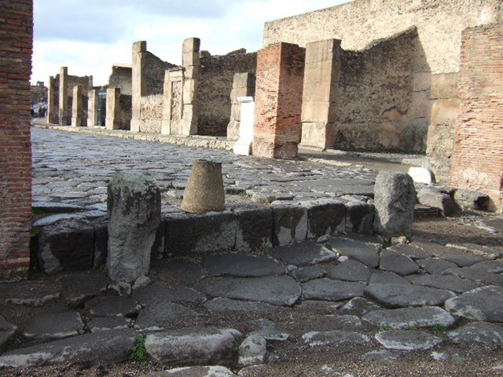Arch of Marcus Holconius Rufus. December 2005. Remains of pillars of the north side of the arch, on right. Looking west through arch along Via dell� Abbondanza.
