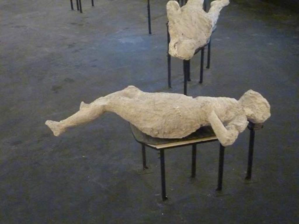 Victim number 4. September 2015. Plaster-cast of victim on display in temporary pyramid in amphitheatre.
According to Dwyer –
The fourth victim was found in the middle of the vicolo, about twenty-five metres from the other three victims.
She was often described as “the pregnant woman”, but her bunched up clothing could have accounted for the impression.
See Dwyer, E., 2010. Pompeii’s Living Statues. Ann Arbor: Univ of Michigan Press, (p.65-69 and fig. 39).