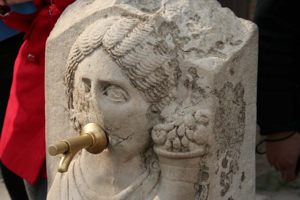 Fountain outside VII.9.67 and VII.9.68. April 2010. Relief of head of Fortuna (Abbondanza) with cornucopia.
Photo courtesy of Klaus Heese.
