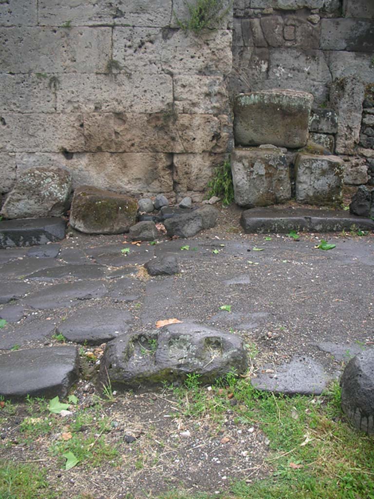 Vesuvian Gate Pompeii. May 2010. Looking west from east side of gate. Photo courtesy of Ivo van der Graaff.
Looking west across north end of the narrow passage, as described by Sogliano. 
“At each of the two northern ends of this narrow passage are two lava blocks [b on the plan, seen earlier above], with inserts for the hinges and posts, for the doors which opened inward. 
These doors, turning on the hinges, closed against a small block of lava [c on the plan, see above], remaining somewhat raised above the ground, allowed the free drainage of water, which ran down from the heights of Mount Vesuvius. 
In the top of the Western Wall there is a square hole and there was undoubtedly another in the opposite wall. These contained the security bar that kept the doors closed.”
See Notizie degli Scavi di Antichità, 1906, p. 97-100.


