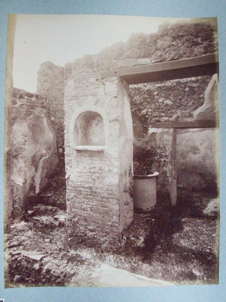 I.3.30 Pompeii. Lararium in peristyle at foot of straight flight of stairs.
Old undated photograph courtesy of the Society of Antiquaries, Fox Collection.
According to Boyce –
in the west wall of the peristyle was an arched niche (h.0.55, w.0.50, d.0.27, h. above floor 1.30).
Its walls were adorned with painted flowers.
On the wall on either side of it, was painted a Lar, 34cms high, holding rhyton and situla.
Below it, there was a single serpent moving towards an altar.
See Boyce G. K., 1937. Corpus of the Lararia of Pompeii. Rome: MAAR 14. (p. 24) 
See Giacobello, F., 2008. Larari Pompeiani: Iconografia e culto dei Lari in ambito domestico. Milano: LED Edizioni, (p.135, no.7)

