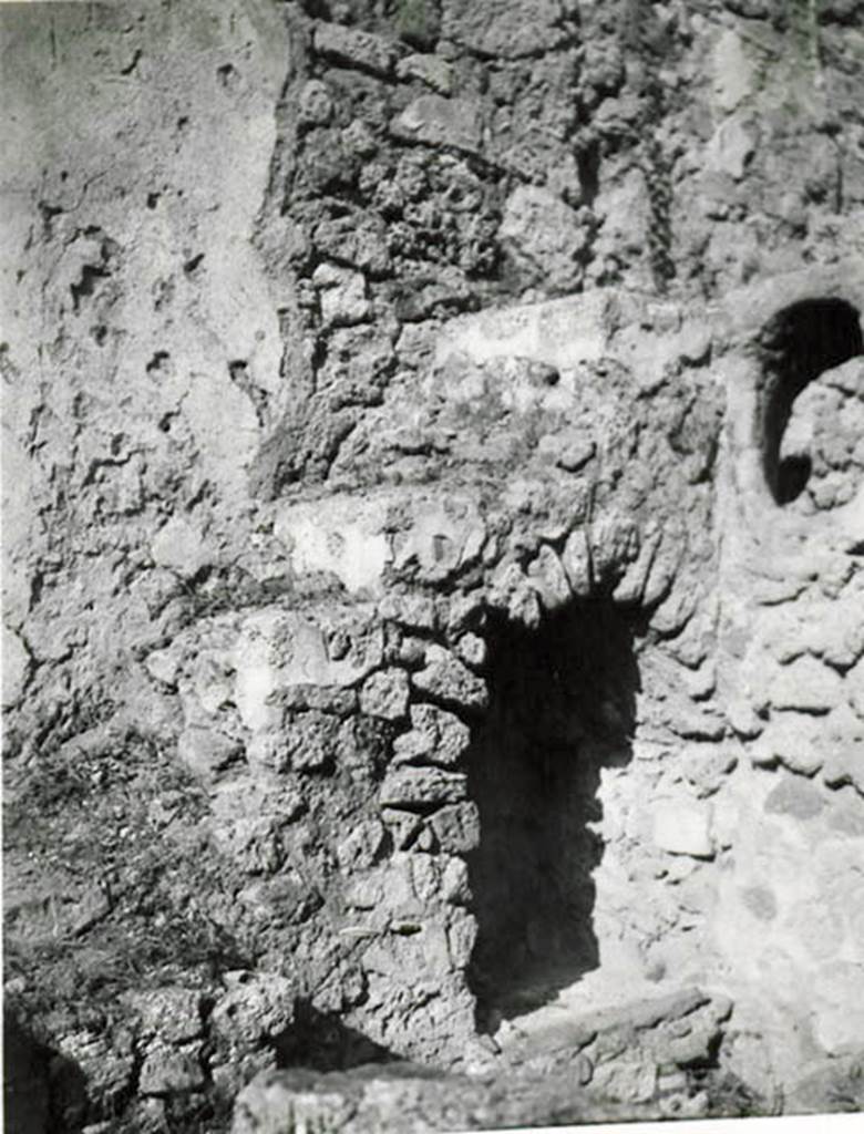I.2.28 Pompeii. 1935 photo taken by Tatiana Warscher.  North-east corner of garden area, with steps to upper floor and recess below.
See Warscher T., 1935. Codex Topographicus Pompeianus: Regio I.2. (no.57), Rome: DAIR, whose copyright it remains.
According to Warscher, �Il lato orientale del peristilio. La scala con sottoscala che conduceva al primo piano e la finestra ovale che illuminava la cucina �k�.
(translation: �The east side of the peristyle. The stairs with understairs, that lead to the first floor, and the oval window that lit the kitchen �k�.)
