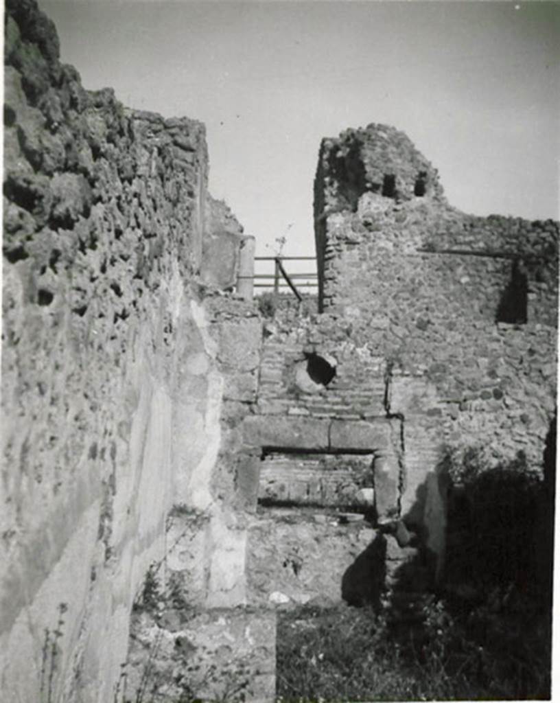 I.3.1 Pompeii. 1935 photograph taken by Tatiana Warscher.
Looking towards oven in north-east corner.
According to Warscher, quoting Fiorelli,  �1.3.1. Officina di un pistor dulcarius, che nella taberna prospiciente la via esposti i prodotti lavorati nell�attigua cella, la quale prendeva lume dalla bottega, avendone altra pi� rozza alle spalle, ed a cui si perveniva passando innanzi al forno; una scala di legno poggiata al muro, ch�� a sinistra della porta, menava alle stanze superiori. Nel foro per il fumo dello forno � incastrata una cornice di terracotta, forse semplicemente un pezzo di anfora. In fondo si vede il muro con fori di traverse della casa No. 3.
(translation: �A workshop of a sweet-pastry maker, that in the shop overlooking the roadway, displayed the products made in the adjacent room, which took its light from the shop, having another rustic room behind, and through which you passed to reach the oven; a wooden ladder rested against the wall, which is to the left of the door, leading to the upper rooms. In the smoke hole in the oven was embedded a terracotta cornice, perhaps simply a piece of amphora. At the rear you see the wall with holes of crossbeams of the house at I.3.3.�)
See Warscher T., 1935. Codex Topographicus Pompeianus: Regio I.3. (no.1), Rome: DAIR, whose copyright it remains.

 
