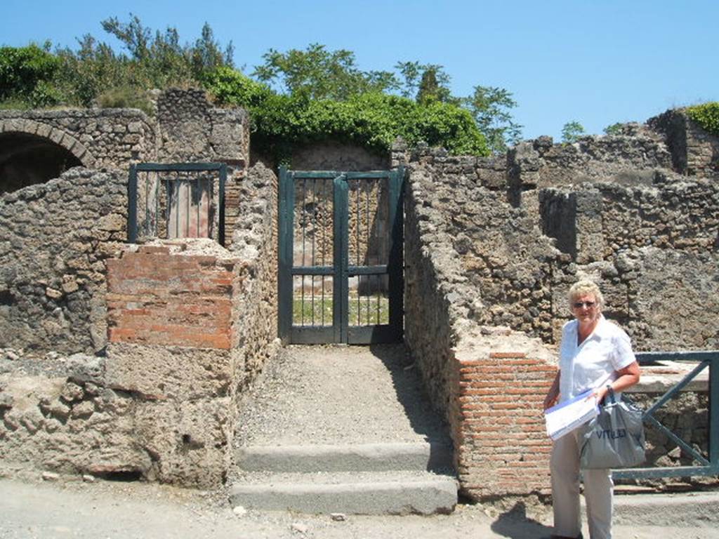I.3.3 Pompeii. May 2005. Entrance on Via Stabiana. According to Warscher, quoting Bull. Inst, 1874, p. 183, she wrote �
Quanto alla pittura decorativa di questa casa, nella parte pi� bassa di essa tutte le pitture mostrano lo stile degli ultimi tempi di Pompei, coll�eccezione della camera a destra della scala. 
Ed alla stessa epoca di quella camera, la terza cio� fra quelle pompeiane, se non m�inganno, appartiene tutto quello che sta intorno al peristilio. Ho parlato appunto di questa casa nel Giorn. d Sc. II, p.456. Chiara � l�identita delle stile riguardo la prima camera dal suo lato occidentale. Il resto delle camere � decorato in uno stile che pu� dirsi quello de�candelabri, perch� divide la parete in tre parti mediante candelabri molto sottili e svelti. E come accennai nel luogo citato, appunto le pitture di queste camere mediante certe piccole particularit� non tanto facili a descriversi ci fanno riconoscere questo stile come affine e probabilmente contemporaneo a quello delle due camere menzionate. Ed allo stile di queste pare appartenesse anche la decorazione del peristilio stesso, bench� poco ne sia conservato.
Que� cambiamenti adunque che, come sopra accennai, sub� la casa in discorso, si rileva dalla stessa decorazione che non ebbero luogo negli ultimi tempi di Pompei, ma probabilmente prima del terramoto dell�a. 63 d.C.
See Warscher, T, 1935: Codex Topographicus Pompejanus, Regio I, 3: (dopo no. 11a), Rome, DAIR.  
