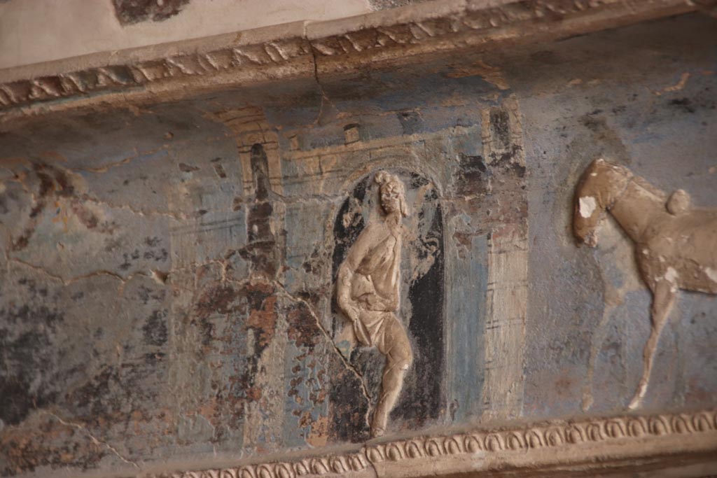 I.6.4 Pompeii. October 2023. Room 16. A servant carries a vase out of the gates of Troy.
Detail from centre of frieze on west wall of sacellum. Photo courtesy of Klaus Heese.