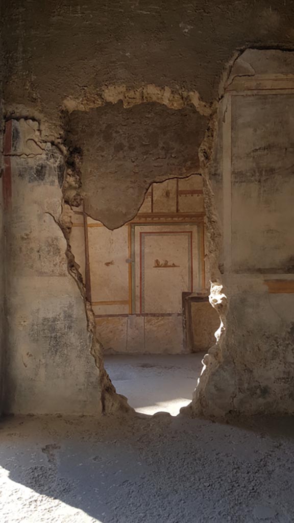 I.7.11 Pompeii. August 2023. 
Looking towards north wall of the cubiculum on east side of atrium, through the hole in north wall from triclinium. 
Photo courtesy of Maribel Velasco.

