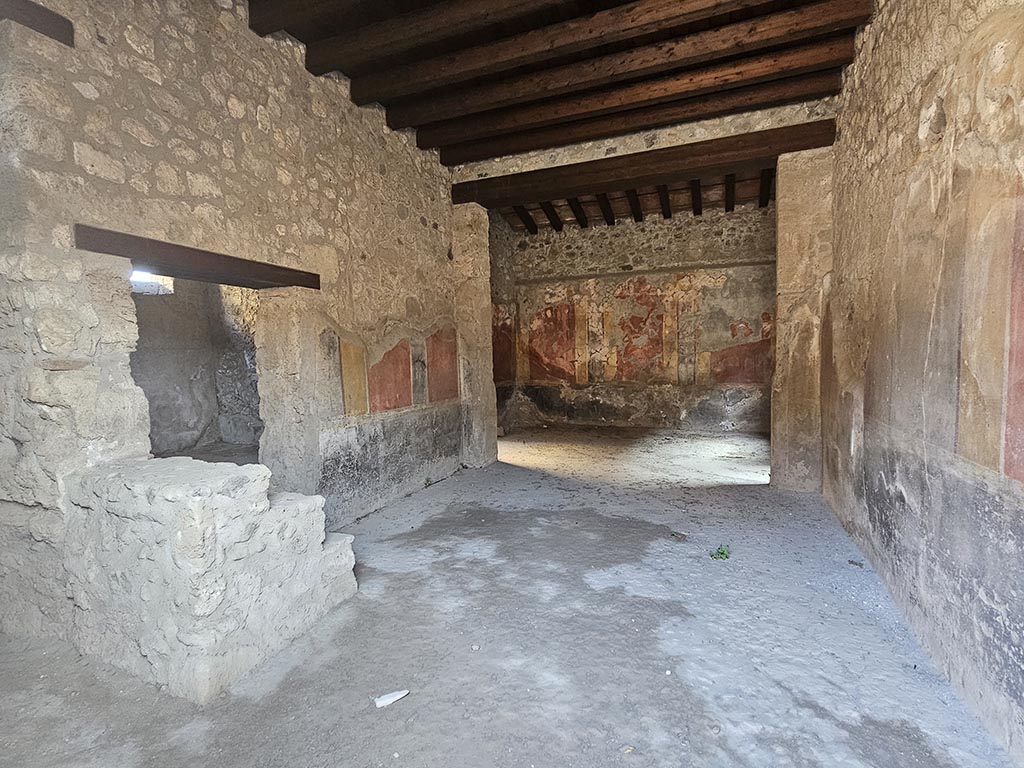 I.10.1, Pompeii. November 2024. 
Looking south along east wall of atrium with doorway to oecus and steps to upper floor, on left. Photo courtesy of Annette Haug.

