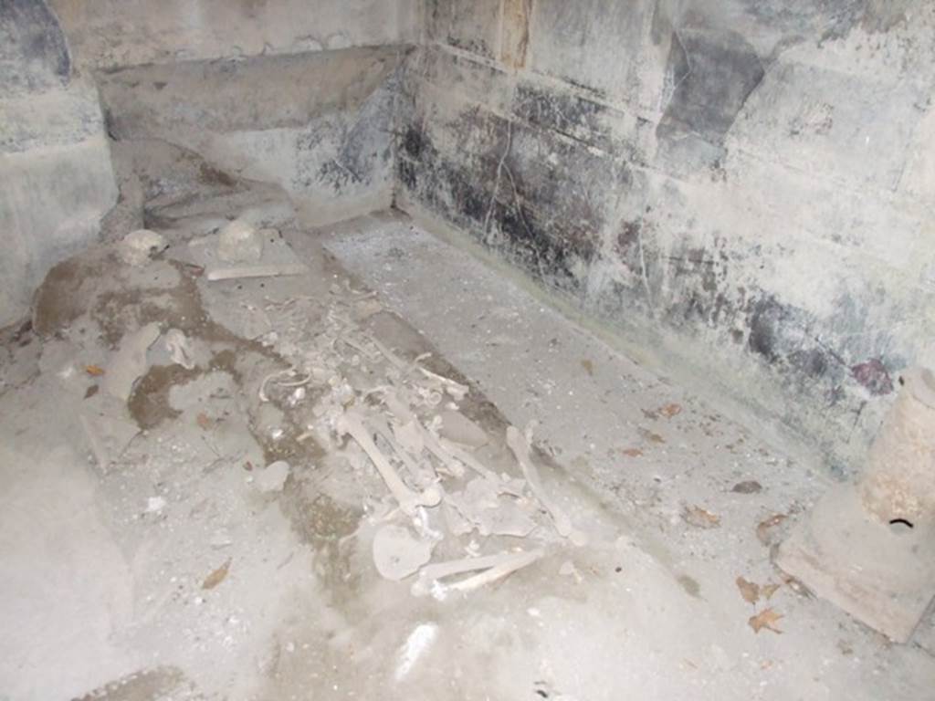 I.10.7 Pompeii. March 2009. Room 12, north-west corner of triclinium, with remains of skeletons. According to Civale, �in the triclinium two people had sought refuge: an adult who was discovered on the floor, his arms clutching the edge of a dining couch, and a second, younger victim his arms folded under the head and legs stretched out on the floor.  
On the ground between the adult�s feet, lay a little cloth bag containing a small hoard of 26 silver coins, amounting to just 104 sesterces.  
In the triclinium, another little heap of 48 coins was found, perhaps also the savings of one of the victims.� See Guzzo, P.G. ed. (2003): Tales from an eruption � (Civale, A: The House of the Craftsman). Milan, Electa; (p.140-41)
