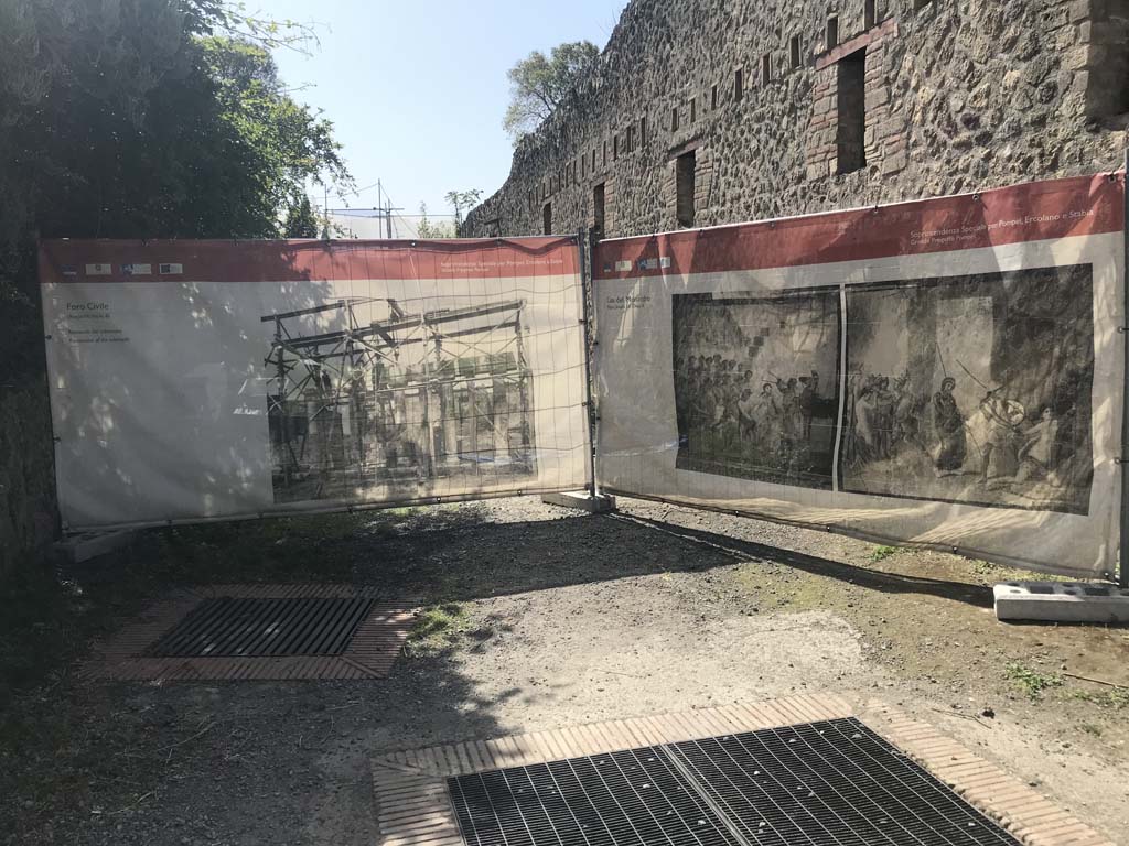 Vicolo di Paquius Proculus, April 2019. 
Looking south along east side fa�ade of House of Menander, the entrance of I.10.15 would be behind the display screen.
I.19 is on the left. 
