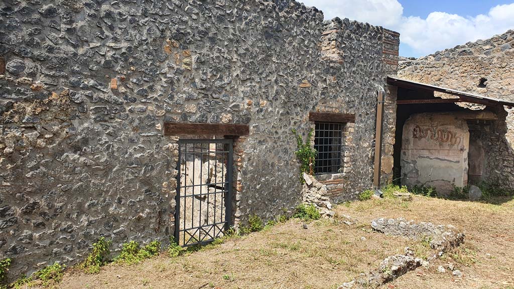 I.11.10 Pompeii. July 2021. 
Looking west across small enclosure towards door into bar-room, window into room for the clients, and painted serpent on exterior wall of latrine..
Foto Annette Haug, ERC Grant 681269 DÉCOR. 
