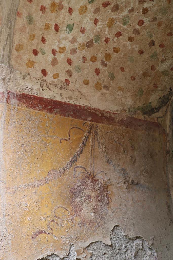 I.12.5 Pompeii. December 2018.
North wall of painted Lararium, with mask hanging from a garland. Photo courtesy of Aude Durand.