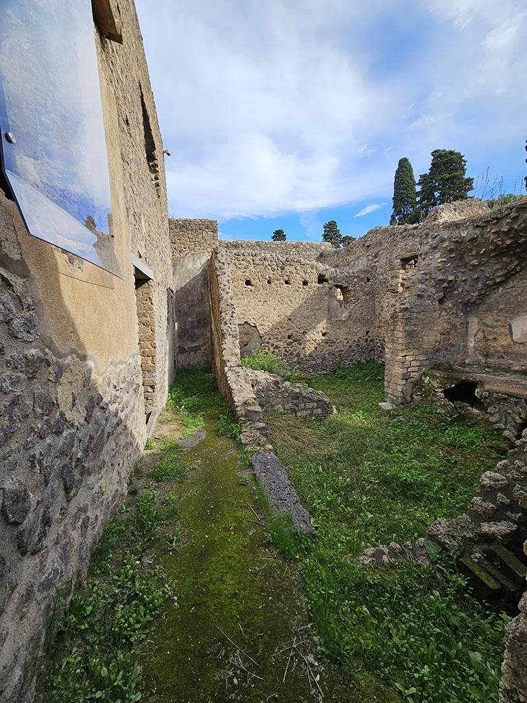 II.4.10 Pompeii. November 2024. 
Looking east from entrance doorway at II.4.10, with kitchen and latrine, on right. Photo courtesy of Annette Haug.

