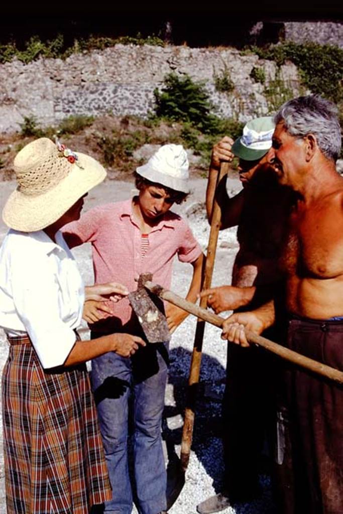 II.8.6 Pompeii. 1972. Showing Wilhelmina how an ancient hoe attached to a modern handle. Photo by Stanley A. Jashemski. 
Source: The Wilhelmina and Stanley A. Jashemski archive in the University of Maryland Library, Special Collections (See collection page) and made available under the Creative Commons Attribution-Non Commercial License v.4. See Licence and use details. J72f0669
