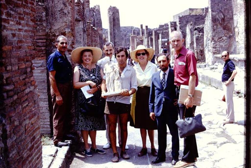 II.8.6 Pompeii, 1973. The statue of Hercules which was found in the lararium in his garden, being carried along the Via dell�Abbondanza.
Photo by Stanley A. Jashemski. 
Source: The Wilhelmina and Stanley A. Jashemski archive in the University of Maryland Library, Special Collections (See collection page) and made available under the Creative Commons Attribution-Non Commercial License v.4. See Licence and use details.
J73f0610
According to Wilhelmina, 
�Guiseppina Cerulli had agreed that Hercules could be returned to his garden for the final photos. He was triumphantly carried along the Via dell�Abbondanza accompanied by admirers and placed again in his shrine. All of her workers wanted their pictures taken with him�.
See Jashemski, W.F., 2014. Discovering the Gardens of Pompeii: Memoirs of a Garden Archaeologist, (p.207).
