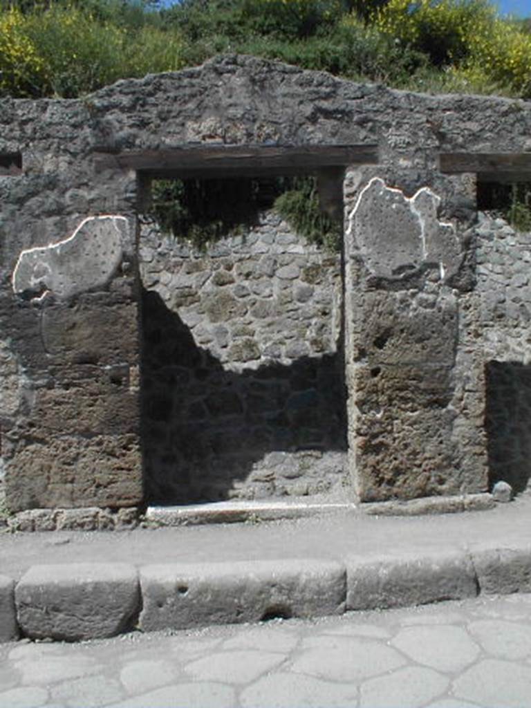III.1.3 Pompeii. May 2005. Entrance doorway, partly excavated
According to Della Corte, on the pilaster to the left, between III.1.2 and 3, was written -
Cn(aeum) Hel[vium] Sabin(um)
aed(ilem) Pacuvius cu[pi]dus rog(at)     [CIL IV 7595]
See Della Corte, M., 1965.  Case ed Abitanti di Pompei. Napoli: Fausto Fiorentino. (p.342)
According to Cooley, this translates as �
Pacuvius eagerly asks for Cn. Helvius as aedile.
See Cooley, A. and M.G.L., 2004. Pompeii : A Sourcebook. London : Routledge. (p.121, F38)
Della Corte also said that on the right pilaster, above an old plaster but brought to light by the fall of the most recent plaster, was painted a large red anchor.  He thought this may have alluded to the activity of the proprietor, perhaps in maritime commerce. Today, the anchor is no longer visible.
