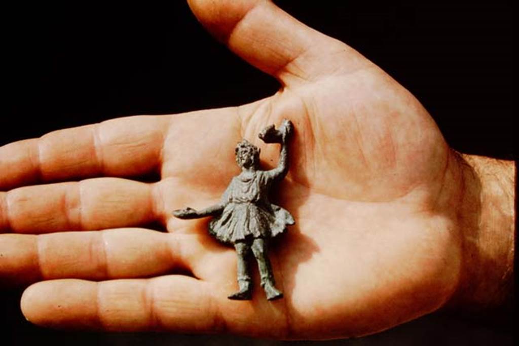 III.7 Pompeii. 1975. Small Lar (7cm, or 2.75 inches high) was found by the original excavators near the triclinium. Photo by Stanley A. Jashemski.   
Source: The Wilhelmina and Stanley A. Jashemski archive in the University of Maryland Library, Special Collections (See collection page) and made available under the Creative Commons Attribution-Non Commercial License v.4. See Licence and use details. J75f0681
According to Wilhelmina, this is now in the Pompeii deposits, inventory number 13467.
