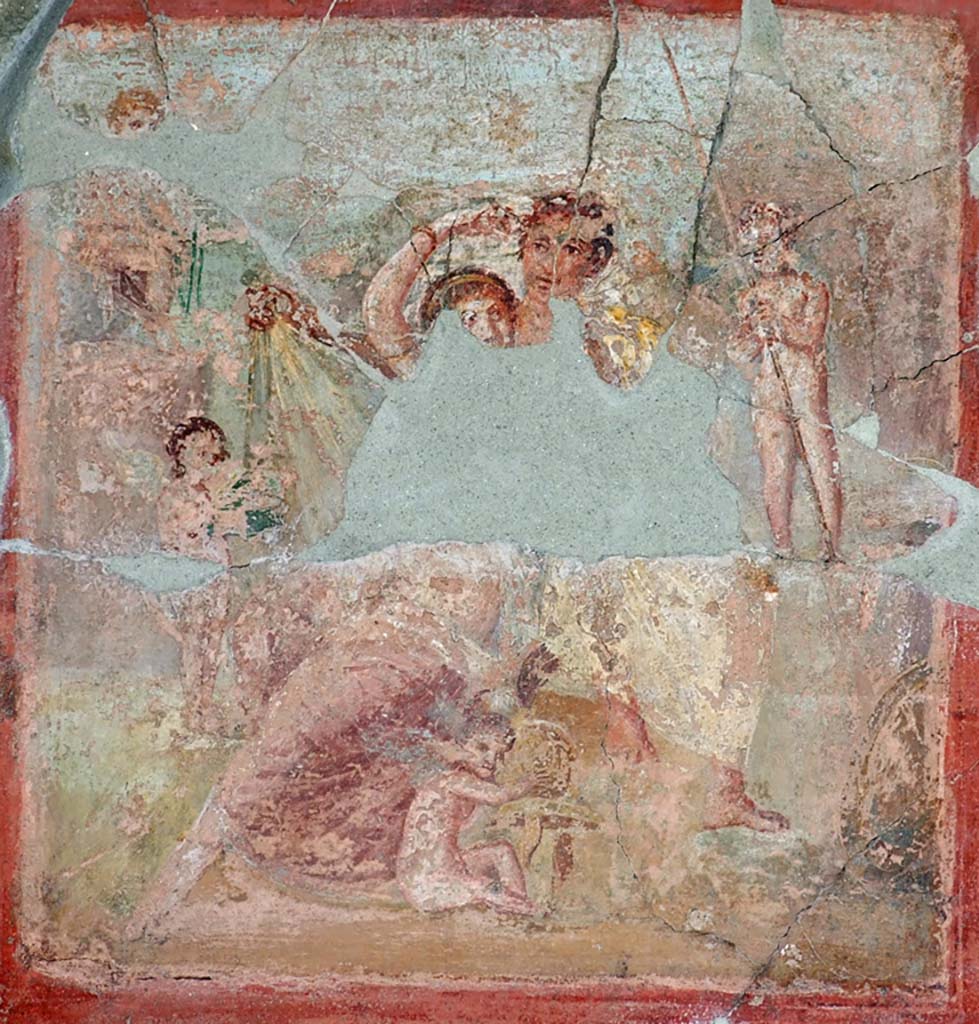V.1.18 Pompeii. March 2009. Exedra “o” on north side of peristyle. North wall.
Remains of wall painting of Venus at her toilette with Mars at her shoulder and with four cupids.
Sogliano refers to them as Ares and Aphrodite. A cupid, sitting between their feet, plays with Mars helmet.
A cupid to the left presents a small green box. Above left a third cupid holds a sword.
The cupid to the right takes the lance. A shield is seen on the lower right.
See Schefold, K., 1957. Die Wände Pompejis. Berlin: De Gruyter. p. 65.
See Sogliano, A., 1879. Le pitture murali campane scoverte negli anni 1867-79. Napoli: Giannini. (p. 34, no.139).
