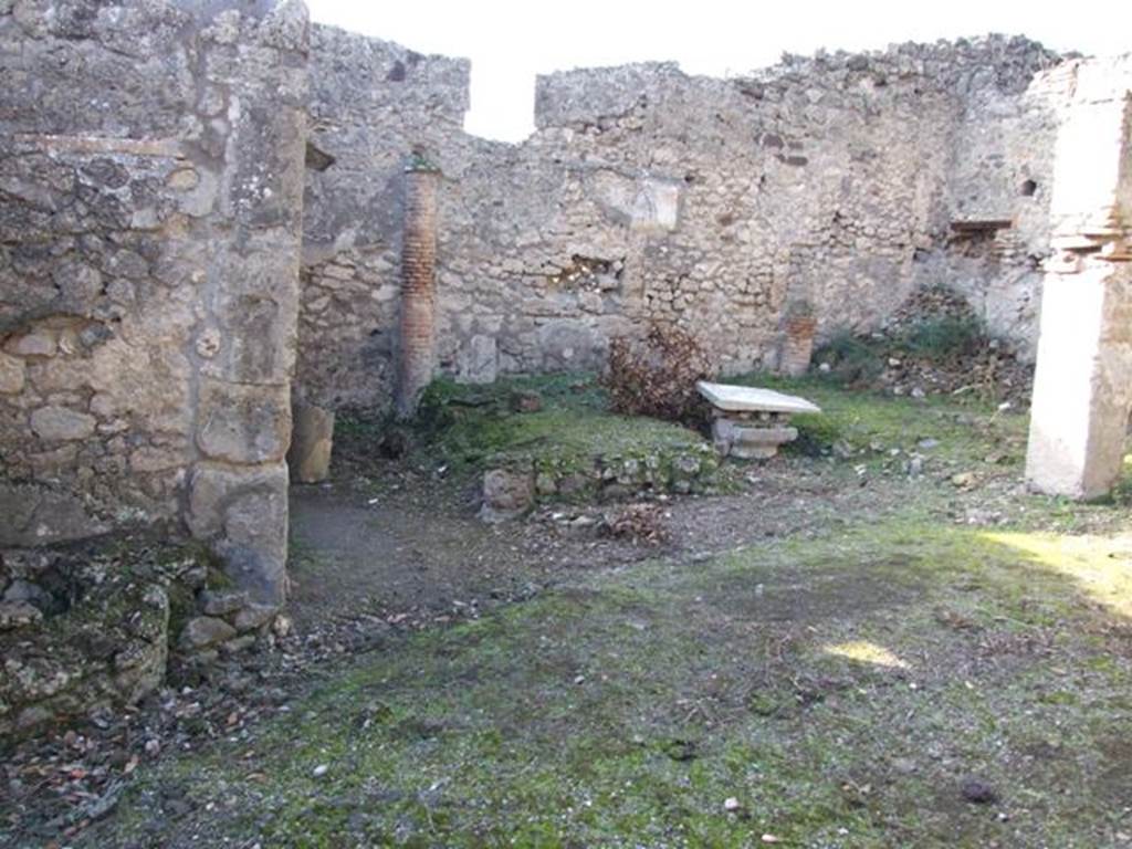 V.2.15 Pompeii. December 2007. Peristyle, looking west at remains of triclinium.
According to Jashemski �
�There was a narrow portico on the east supported by three columns which were joined by a low wall; the wider portico on the north in addition to the corner column was supported by a pillar. Between the corner column and the pillar stood a rectangular marble table mounted on two supports.
On the west, the garden was enclosed by a low wall which was shaped to leave room for the cistern-opening in the south-west corner. 
There was a gutter along the outer edge of the garden.
Built against the west wall was a masonry triclinium (l. medius, 4.20m; l . imus and l. summus, 3.30m; a rectangular table between the couches 0.93 x 0.57m).
It was shaded by a pergola supported by two columns in front, two engaged columns at the rear. 
The columns were covered in yellow stucco on which vines were painted. 
The holes in which the little poles which supported the vines were inserted are still visible.�
See Jashemski, W. F., 1993. The Gardens of Pompeii, Volume II: Appendices. New York: Caratzas. (p.111).
