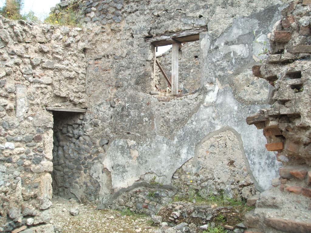 V.2.d Pompeii. May 2005. Room “b” on south side of atrium.
South wall of room with corner bench and cistern, and doorway to room “i” the kitchen and latrine, in south-east corner.
