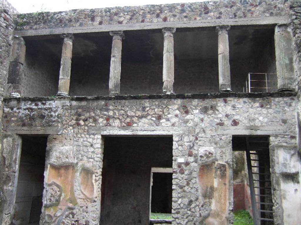V.2.h Pompeii. December 2005. South side of atrium. Doorways to cubiculum �g�, tablinum �f� (in centre), and room �e� with stairs. According to NdS, the floor of the atrium was Opus signinum, and the walls were covered with a rustic white plaster, except the two walls flanking the doorway to the tablinum, which were decorated with a yellow background and a black dado. On the yellow part was a painted peacock of more or less its natural size, before which, on the wall to the right, was a basket full of grapes, and on that to the left were fruits (pomegranates?) placed on the ground. In both of the walls to the sides of the tablinum, traces of fire could be seen.