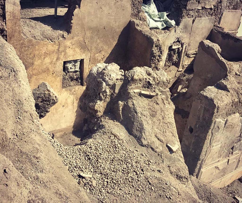 V.2.Pompeii. Casa di Orione. May 2018. Room A17 on the south side during excavation.
Photograph © Parco Archeologico di Pompei.
This room was the kitchen, a “service room” recognised by its simple decoration and the presence on the floor
of various artefacts from table and pantry (cooking pots and tablewares) and amphorae, as well as from the finding near to the east wall of a square structure that defined a masonry hearth. There at the time of excavation, the ash of the last baking/cooking was still preserved, covered by the upper portion of an amphora which was to serve as a lid. Presumably, the last cooked meal, and perhaps never eaten, by the owner of the house.
See Osanna M, 2019. Pompei. Il tempo ritrovato. Le Nuove Scoperte. Milano: Rizzoli, (p.99).