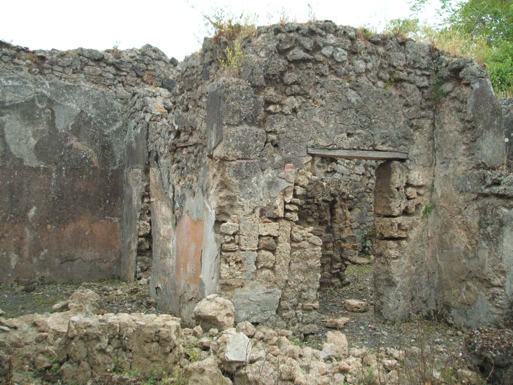 V.3.11 Pompeii. May 2005. South side of atrium, with doorways to triclinium and kitchen.
When excavated, the pilaster between the doorways was seen to show an imitation marble dado, and the middle zone was black with panels.
See Bragantini, de Vos, Badoni, 1983. Pitture e Pavimenti di Pompei, Parte 2. Rome: ICCD. (p.79, atrium (A))
