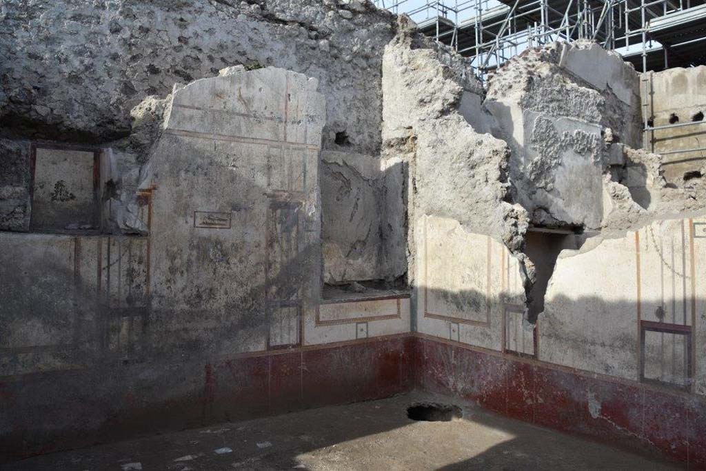 V.3 Pompeii. Casa del Giardino. October 2018. Ambiente 7. West wall with white walls, architectural painting and two niches. Below is a red zoccolo with plants. The north wall is to the right with the square niche of ambiente 8 behind.

Ambiente 7. Parete ovest con pareti bianche, pittura architettonica e due nicchie. Sotto c'è uno zoccolo rosso con piante. La parete nord è a destra con la nicchia quadrata dell'ambiente 8 dietro.

Photograph © Parco Archeologico di Pompei.