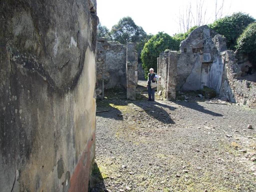 V.4.c Pompeii. March 2009. Room G, south wall of tablinum, on left. Looking west across atrium to entrance corridor fauces A.  According to Sogliano, the two pillars of the fauces on the west side of the atrium were painted in yellow. However, this colour was only preserved in the pillar to the left, having mostly changed to red on the right pillar because of the oxidation of colors due to the fire that developed at the time of the catastrophe. The surface of the latter pillar was wider, and found in the centre was a painting representing a flying Swan with a ribbon between its feet and beak. See Notizie degli Scavi, 1905, (p.131). Note: Sogliano would have probably been describing the “wider” pillar on the right, as the wider pillar on the left in our photo.
