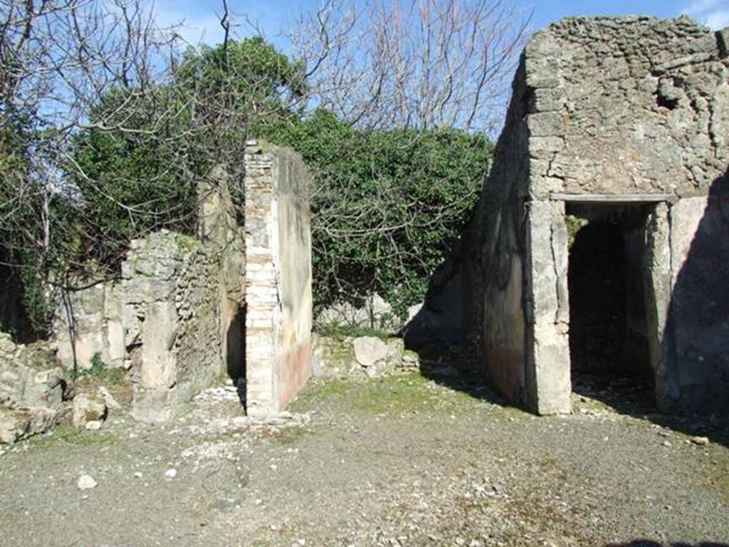 V.4.c Pompeii. March 2009. Room B, the atrium, looking east. Looking across atrium to doorways to room F, on left, room J, corridor to garden, room G, tablinum, and room H, cubiculum.  When excavated the atrium had flooring similar to that of the fauces, opus signinum/cocciopesto.
V.4.c Pompeii (described as second house after that of Lucrezio Frontone).
Found on 15th March 1902, between the upper layers of a room near the tablinum, was an oxidised statuette (100mm high) of a bearded and crowned Hercules, leaning with the weight of his body on his right leg, since the left leg was slightly bent. In his right hand he held the club pointing downwards, and in his left hand he held the apples of the Hesperides; the lion�s skin was hanging on his left forearm. If he was beardless, he would have very closely resembled the Hercules Righetti of the Vatican Rotunda. Also found were � a bronze cylindrical bell with an iron ringer/clapper. An oxidised medium and small bronze coin. A glass bottle with a spherical belly. Found on the 24th March in the same place was a terracotta single-burner lamp, with a ring handle. See Notizie degli Scavi di Antichit�, 1902, (p.213)

