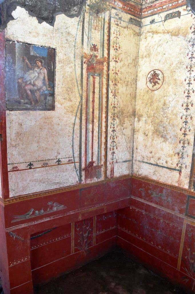 V.6.12 Pompeii. February 2019. Amb. 9. Cubiculum. Corner with Leda fresco and bed niche. 
A small painted panel can be seen at the top of each of the two walls.
The entire Leda room is characterised by sophisticated Fourth Style decorations, with delicate floral embellishments, interspersed by griffins with cornucopia, winged cupids, still lifes and scenes of combat between animals. The harmony of these exquisite designs even extended to the ceiling, which completely collapsed under the weight of the lapilli, and whose fragments were recovered by restorers and used to reconstruct the story. 

Cubiculum. Angolo con affresco Leda e nicchia letto.
Un piccolo pannello dipinto può essere visto nella parte superiore di ciascuna delle due pareti.
Decori raffinati di IV stile caratterizzano l'intera stanza di Leda, con delicati ornamenti floreali, intervallati da grifoni con cornucopie, amorini volanti, nature morte e scene di lotte tra animali. Finanche sul soffitto, rovinosamente crollato sotto il peso dei lapilli, si estendeva l'armonia di questi pregiati disegni, i cui frammenti sono stati recuperati dai restauratori per ricomporne la trama.

Photograph © Parco Archeologico di Pompei.
