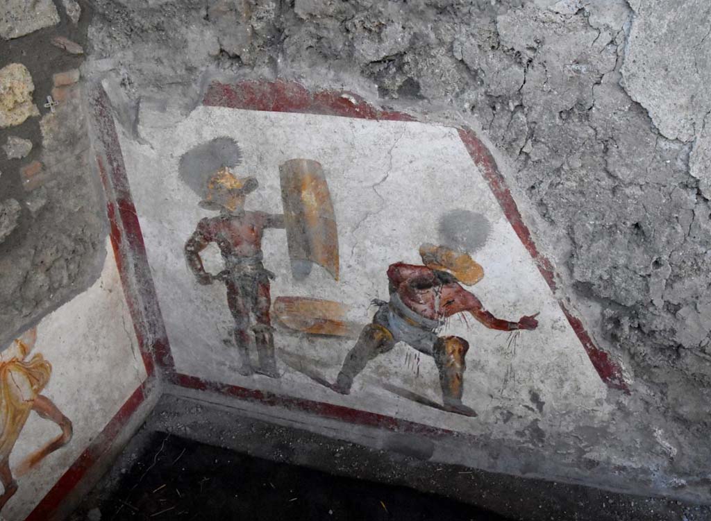 Two gladiators at the end of the fight, one wins the other succumbs.
The fresco of about 1.12 meters x 1.5 meters, found in a room behind the widening of the intersection of the Vicolo dei Balconi and the Vicolo delle Nozze D’Argento, has a trapezoidal shape, as it was located in the basement, perhaps of a shop. Above the painting we can see the imprint of the wooden staircase. 

It is very likely that this place was frequented by gladiators, it is in the Regio V, not far from the caserma dei gladiatori from where, among other things, come the highest number of graffiti inscriptions related to their world. In this gladiatorial fresco of a Murmillo and a Thracian, of particular interest is the extremely realistic representation of the wounds, such as that on the wrist and chest of the succumbing gladiator, which let out the blood that also bathes the legs.  We don't know what the final outcome of this fight was. You could die or have grace. In this case there is a singular gesture that the wounded Thracian makes with the hand, perhaps, to plead for salvation; it is the gesture of ad locutia, usually made by the emperor or the general to grant grace.

Due gladiatori al termine del combattimento, l’uno vince l’altro soccombe
L’affresco di circa 1,12 mt x 1,5mt, rinvenuto in un ambiente alle spalle dello slargo di incrocio tra il Vicolo dei Balconi e il vicolo delle Nozze d’Argento, ha forma trapezoidale, in quanto era collocato nel sottoscala, forse di una bottega. Si intravede al di sopra della pittura, l’impronta della scala lignea.

E’ molto probabile che questo luogo fosse frequentato da gladiatori. Siamo nella Regio V, non lontani dalla caserma dei gladiatori da dove, tra l’altro, provengono il numero più alto di iscrizioni graffite riferite a questo mondo. In questo affresco di un Mirmillone e un Trace, di particolare interesse è la rappresentazione estremamente realistica delle ferite, come quella al polso e al petto del gladiatore soccombente, che lascia fuoriuscire il sangue e bagna i gambali.  Non sappiamo quale fosse l’esito finale di questo combattimento. Si poteva morire o avere la grazia. In questo caso c’è un gesto singolare che il trace ferito fa con la mano, forse, per implorare salvezza; è il gesto di ad locutia, abitualmente fatto dall’imperatore o dal generale per concedere la grazia.
http://pompeiisites.org/comunicati/laffresco-dei-gladiatori-combattenti-nuova-scoperta-nella-regio-v/

Photograph © Parco Archeologico di Pompei.
